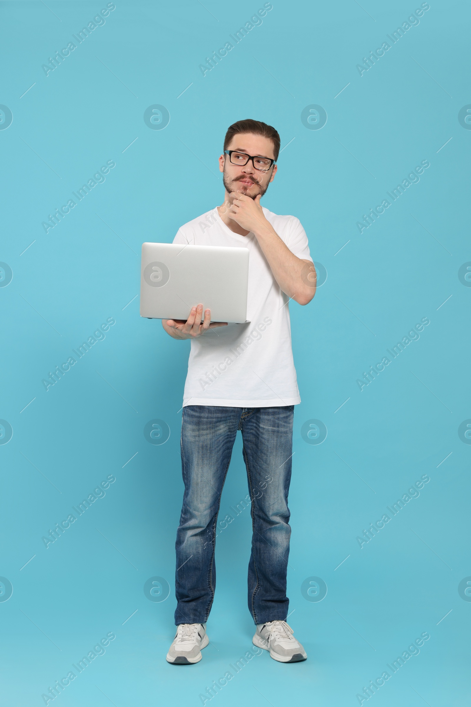 Photo of Pensive man using laptop on light blue background