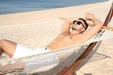 Young man relaxing in hammock on beach