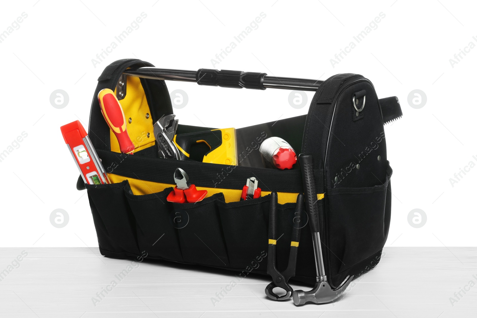 Photo of Bag with different tools on wooden table against white background