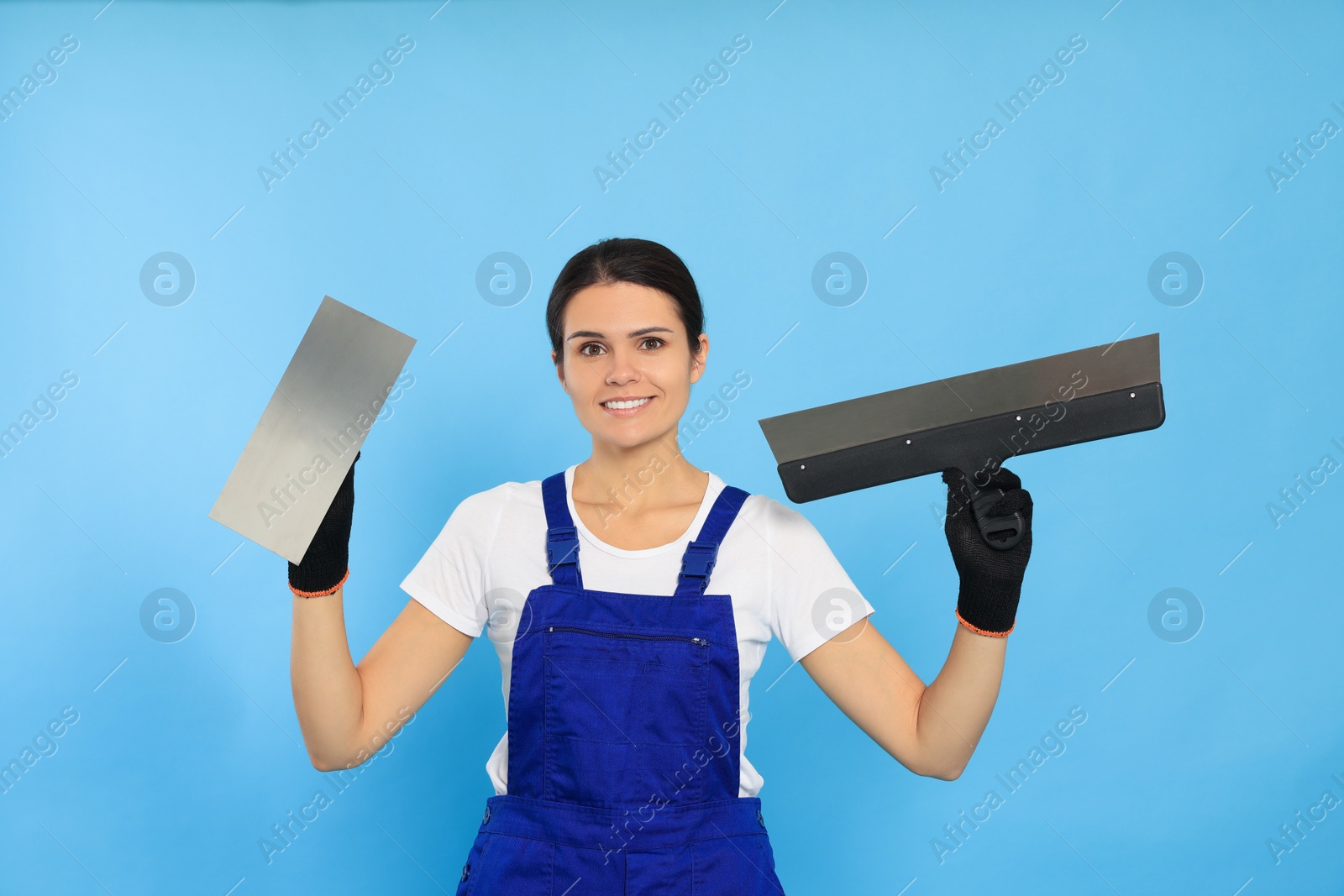 Photo of Professional worker with putty knives on light blue background