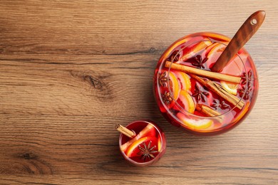 Photo of Glass and bowl of delicious aromatic punch drink on wooden table, flat lay. Space for text