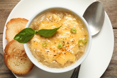 Photo of Tasty homemade french onion soup served on wooden table, top view