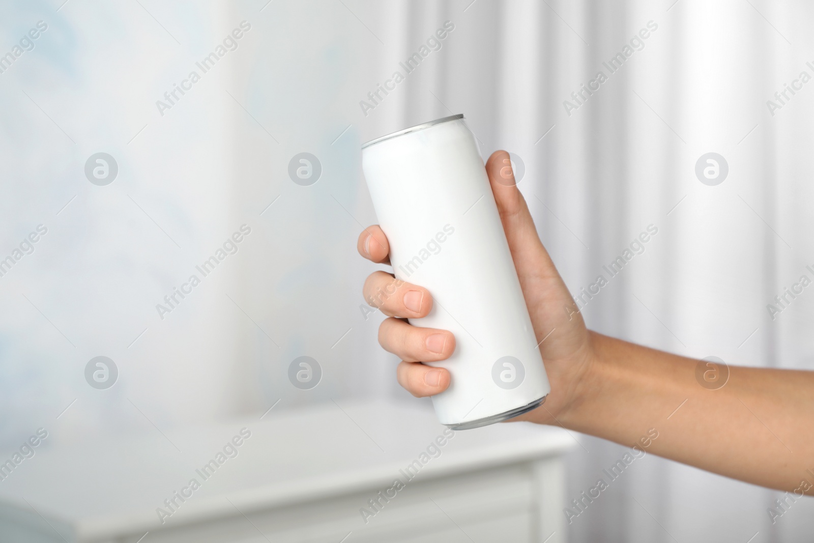 Photo of Woman holding aluminum can with beverage on blurred background, closeup. Space for design