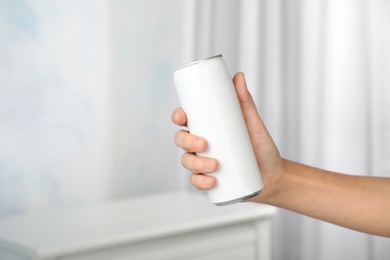 Woman holding aluminum can with beverage on blurred background, closeup. Space for design