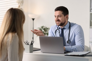 Professional doctor working with patient at white table in hospital