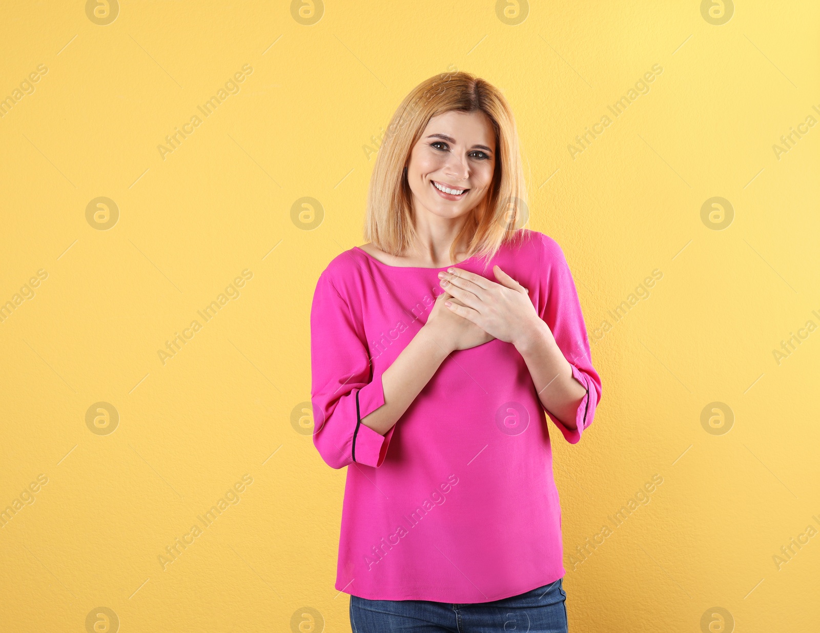 Photo of Portrait of woman holding hands near heart on color background