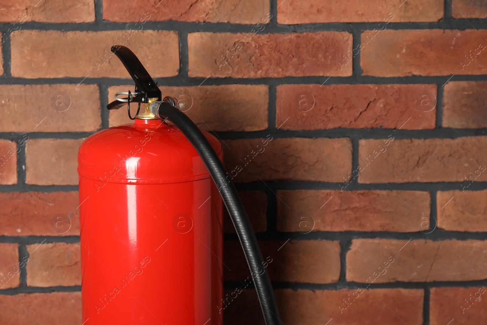 Photo of One red fire extinguisher near brick wall, space for text