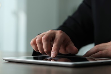 Photo of Closeup view of man using new tablet at desk indoors