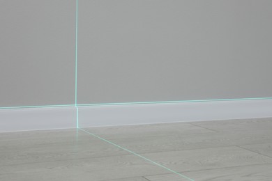 Photo of Cross lines of laser level on wall and floor indoors