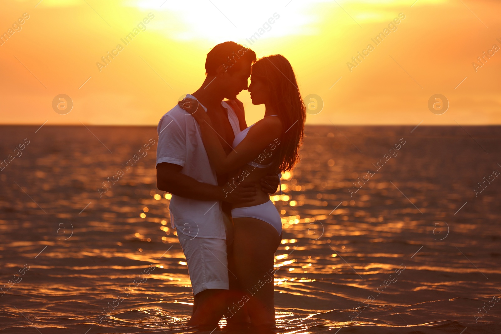 Photo of Happy young couple spending time together on sea beach at sunset