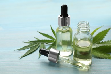 Photo of Hemp leaves, CBD oil and THC tincture on light blue wooden table