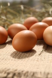 Photo of Fresh chicken eggs on burlap fabric, closeup