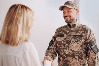 Photo of Psychologist shaking hands with military officer in office