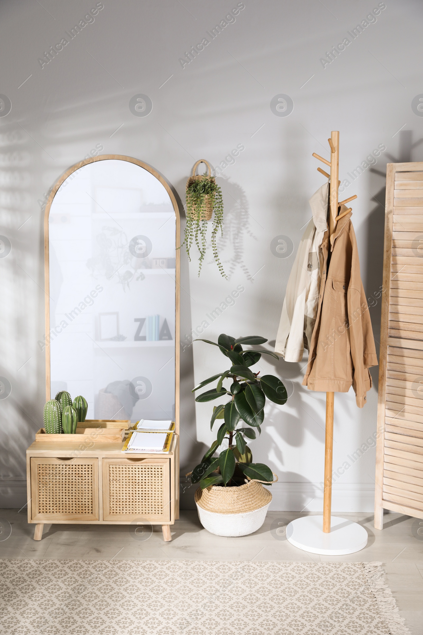 Photo of Stylish hallway room interior with wooden commode, coat rack and large mirror