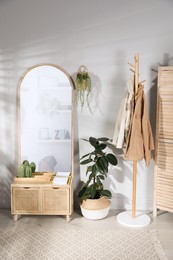 Stylish hallway room interior with wooden commode, coat rack and large mirror