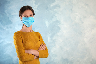 Woman with disposable mask on face against light blue background. Space for text