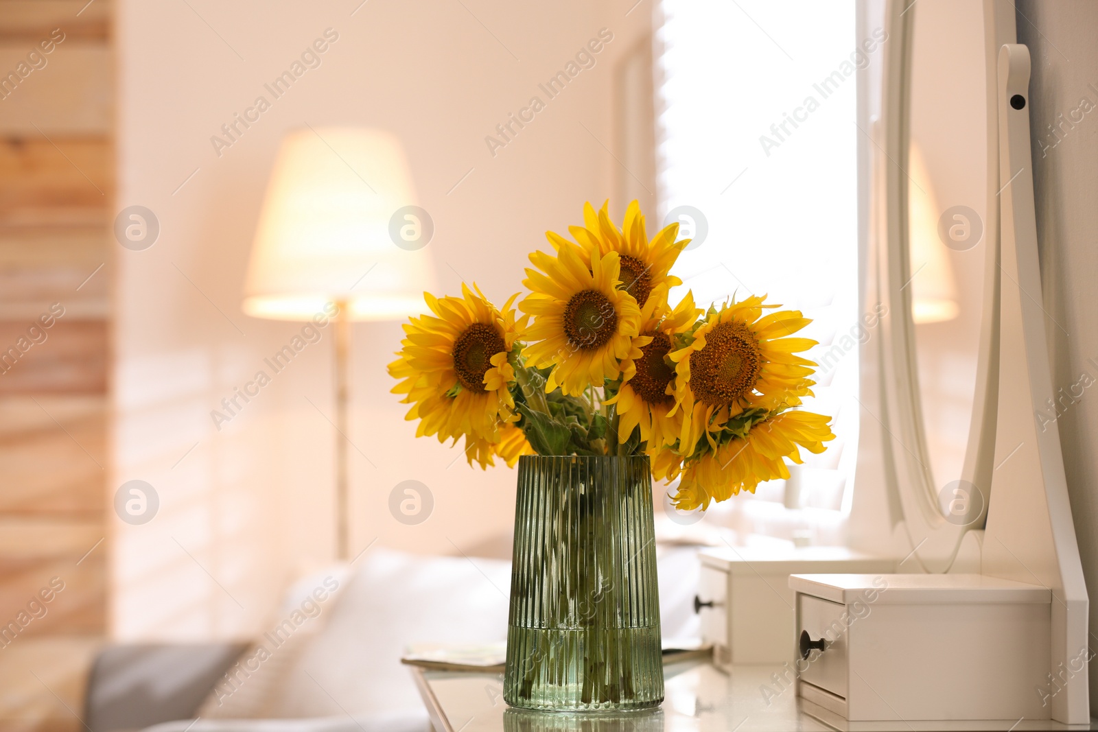 Photo of Beautiful bouquet of sunflowers in vase on white table indoors. Space for text