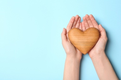 Photo of Woman holding heart on blue background, top view with space for text. Donation concept