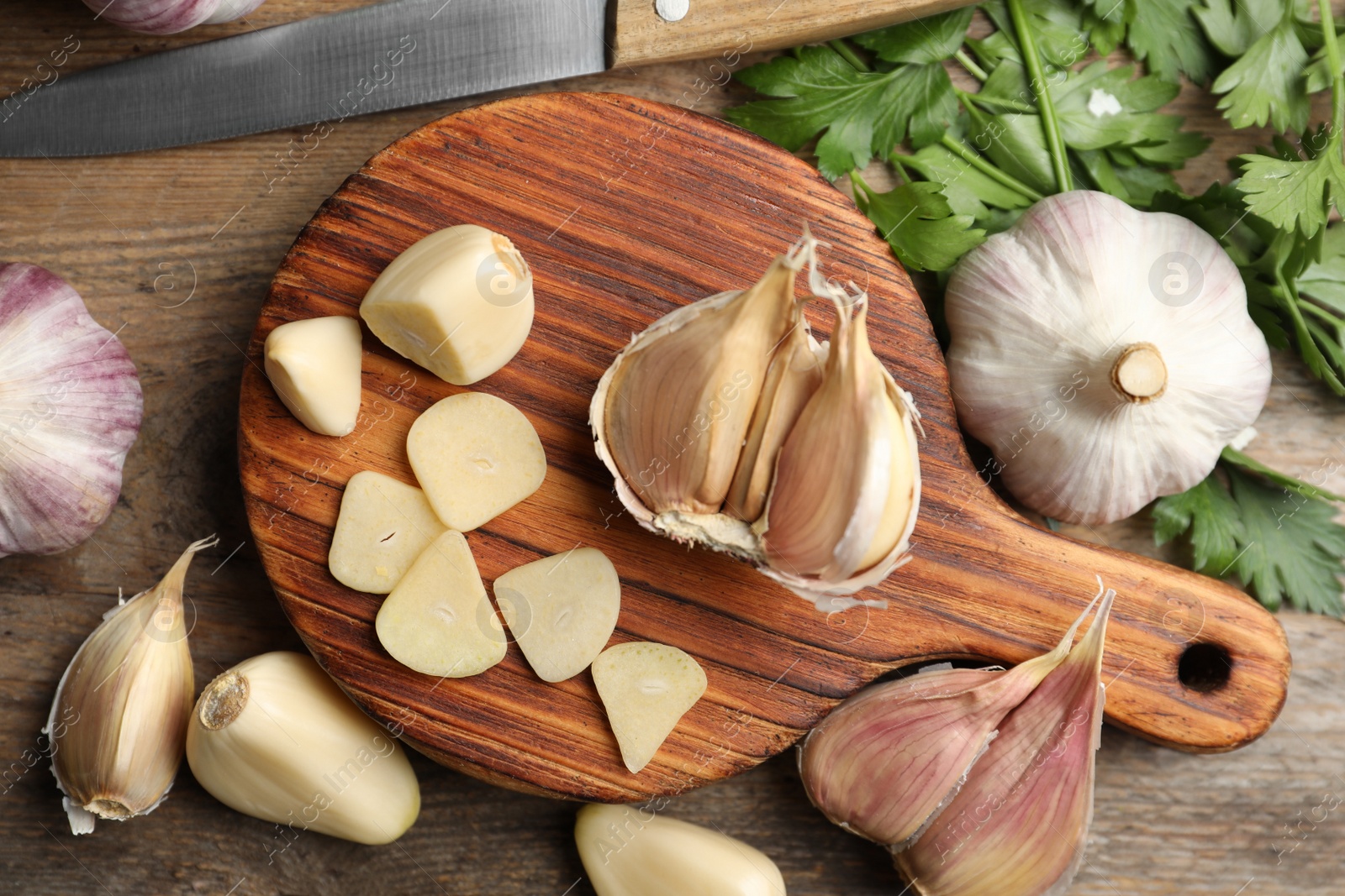 Photo of Flat lay composition with fresh sliced and whole garlic on wooden table. Organic product