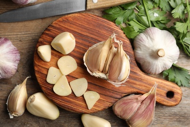 Photo of Flat lay composition with fresh sliced and whole garlic on wooden table. Organic product