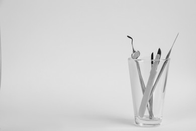 Photo of Glass holder with set of dentist's tools on light background. Space for text