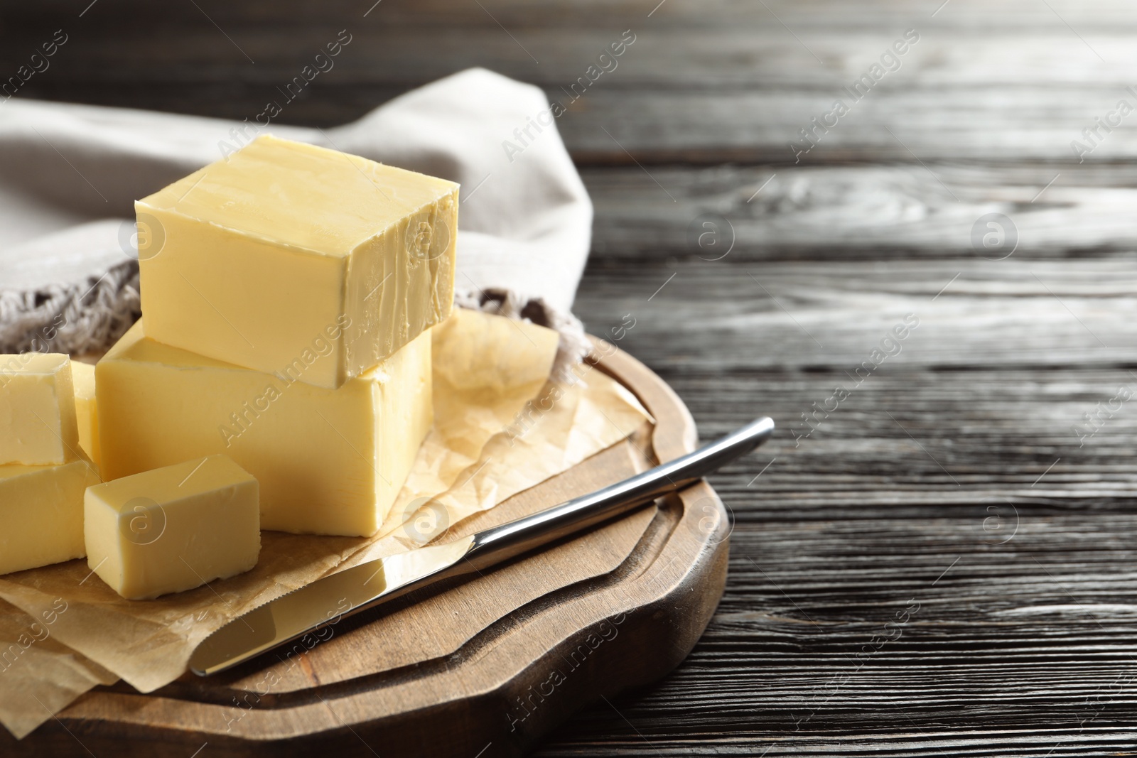 Photo of Wooden board with fresh butter and knife on table, space for text