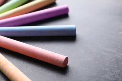 Photo of Pieces of color chalk on blackboard, closeup. Space for text