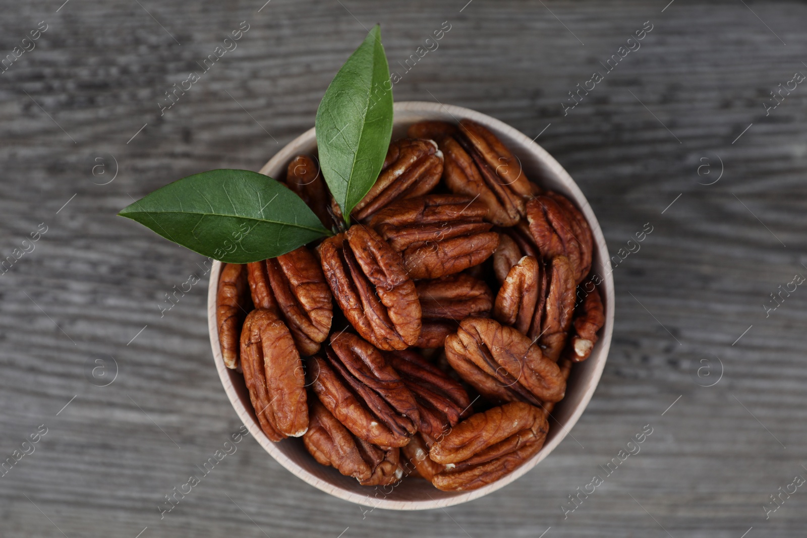 Photo of Tasty pecan nuts on grey wooden table, top view