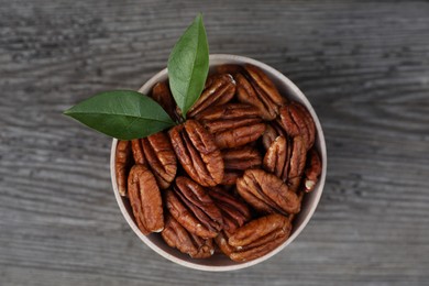 Tasty pecan nuts on grey wooden table, top view