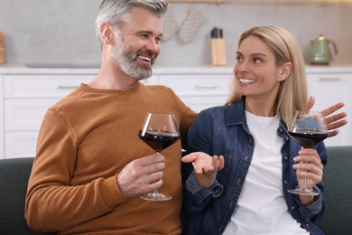 Happy affectionate couple with glasses of wine on sofa at home. Romantic date