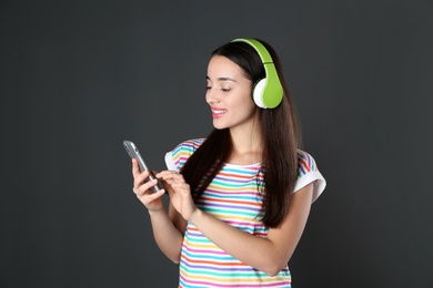 Photo of Beautiful young woman listening to music with headphones on black background