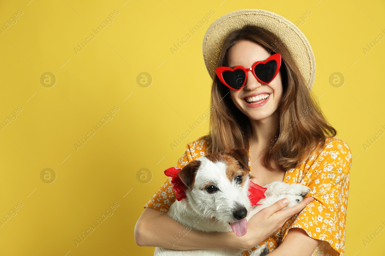 Photo of Young woman with her cute Jack Russell Terrier on yellow background, space for text. Lovely pet