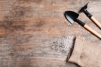 Photo of Flat lay composition with gardening tools and chemical fertilizer on wooden table. Space for text