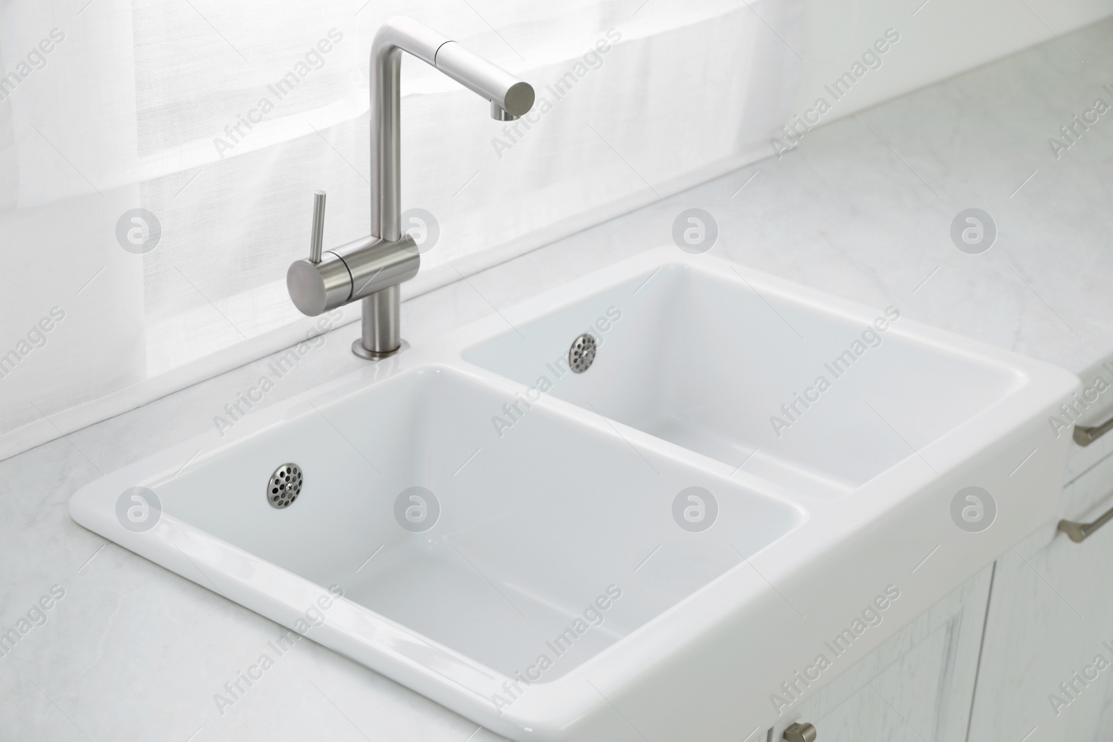 Photo of Modern sink and water tap near window in kitchen. Interior design