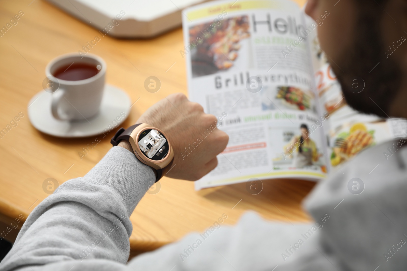 Image of Businessman checking home security system via smartwatch app at table in cafe, closeup.  room through CCTV camera on display