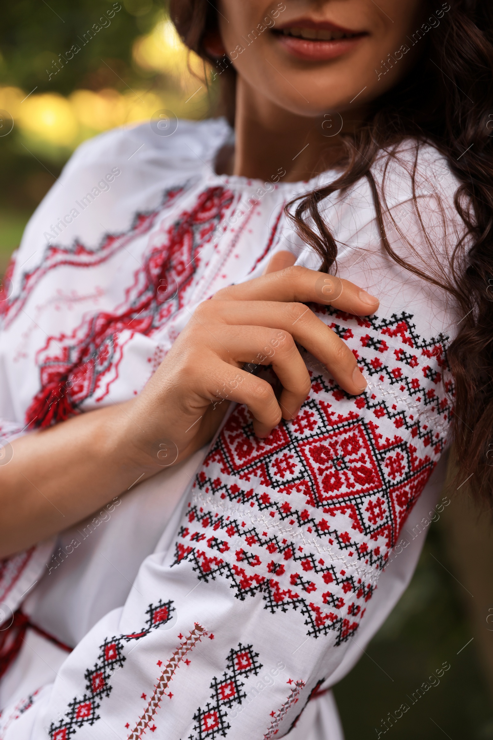 Photo of Woman in beautiful embroidered shirt outdoors, closeup. Ukrainian national clothes