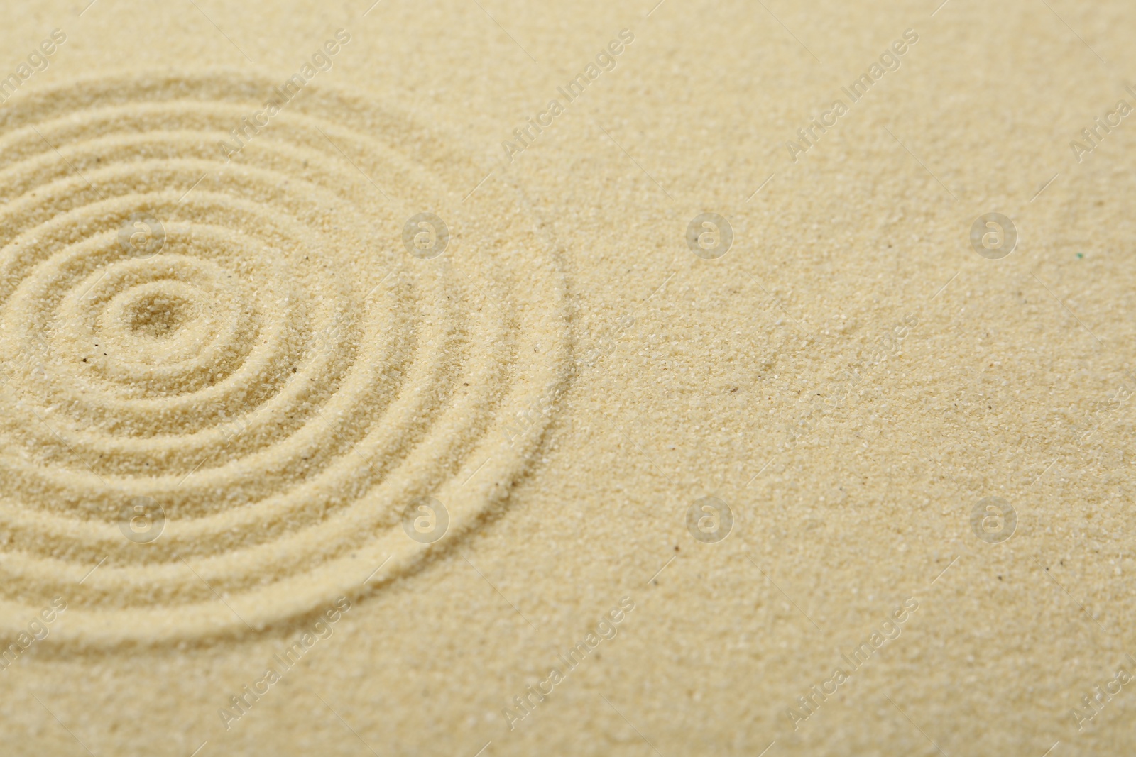 Photo of Zen rock garden. Circle pattern on beige sand