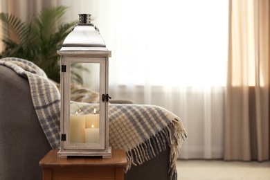 Photo of Decorative lantern with candles in living room interior. Space for text