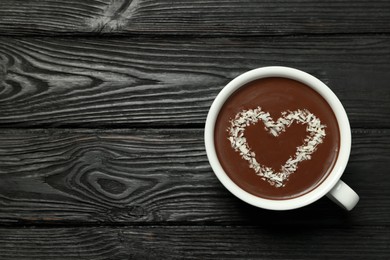 Cup of hot chocolate with heart shaped decoration on black wooden table, top view. Space for text