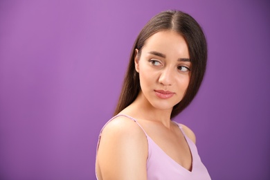 Portrait of beautiful young woman on purple background