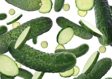 Image of Fresh green cucumbers falling on white background