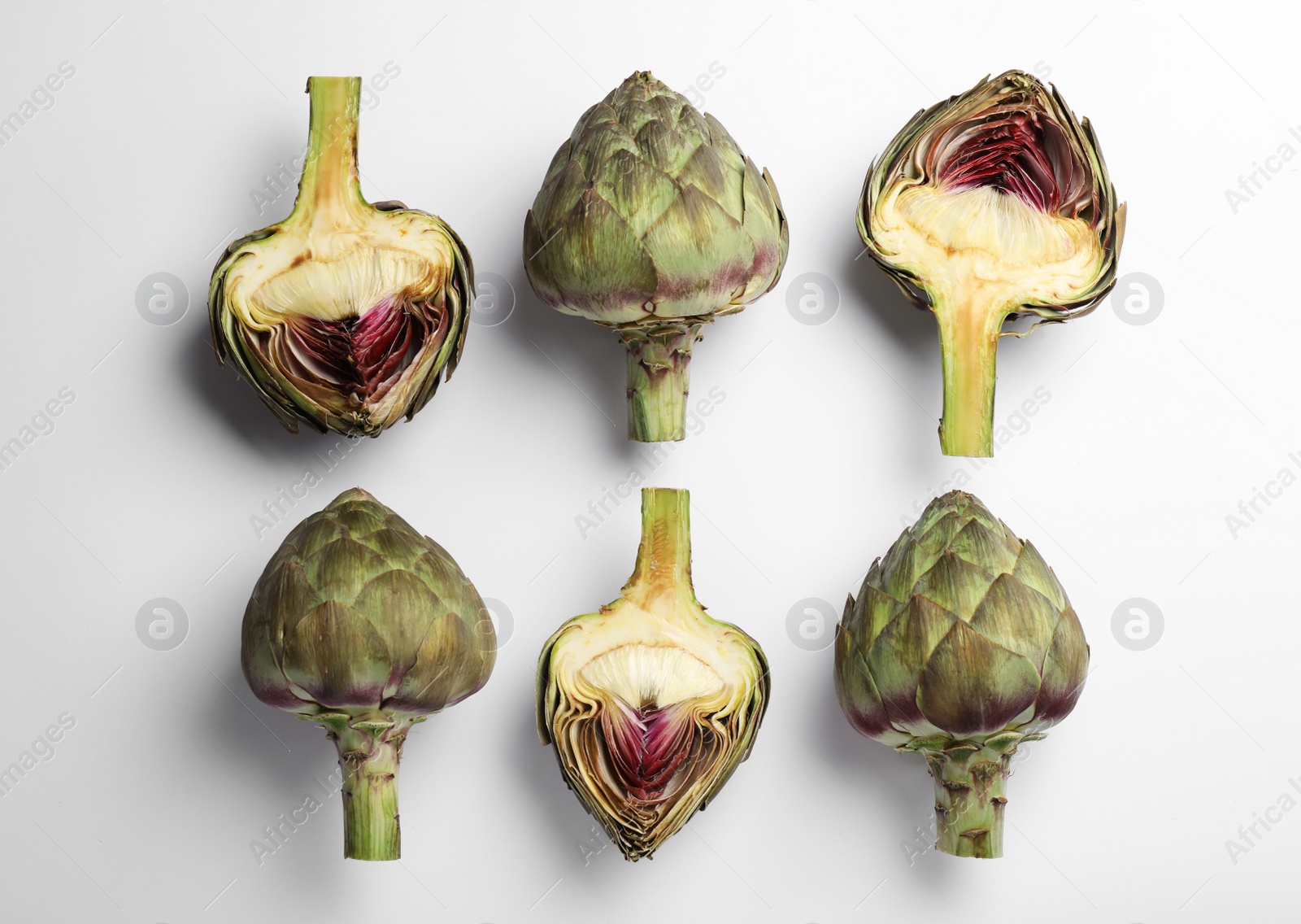 Photo of Cut and whole fresh raw artichokes on white background, flat lay