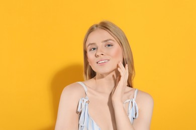 Beautiful young woman posing on orange background