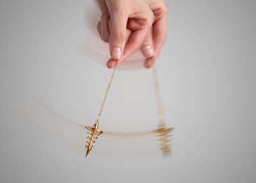 Image of Hypnosis session. Woman swinging pendant on light background, closeup. Motion effect