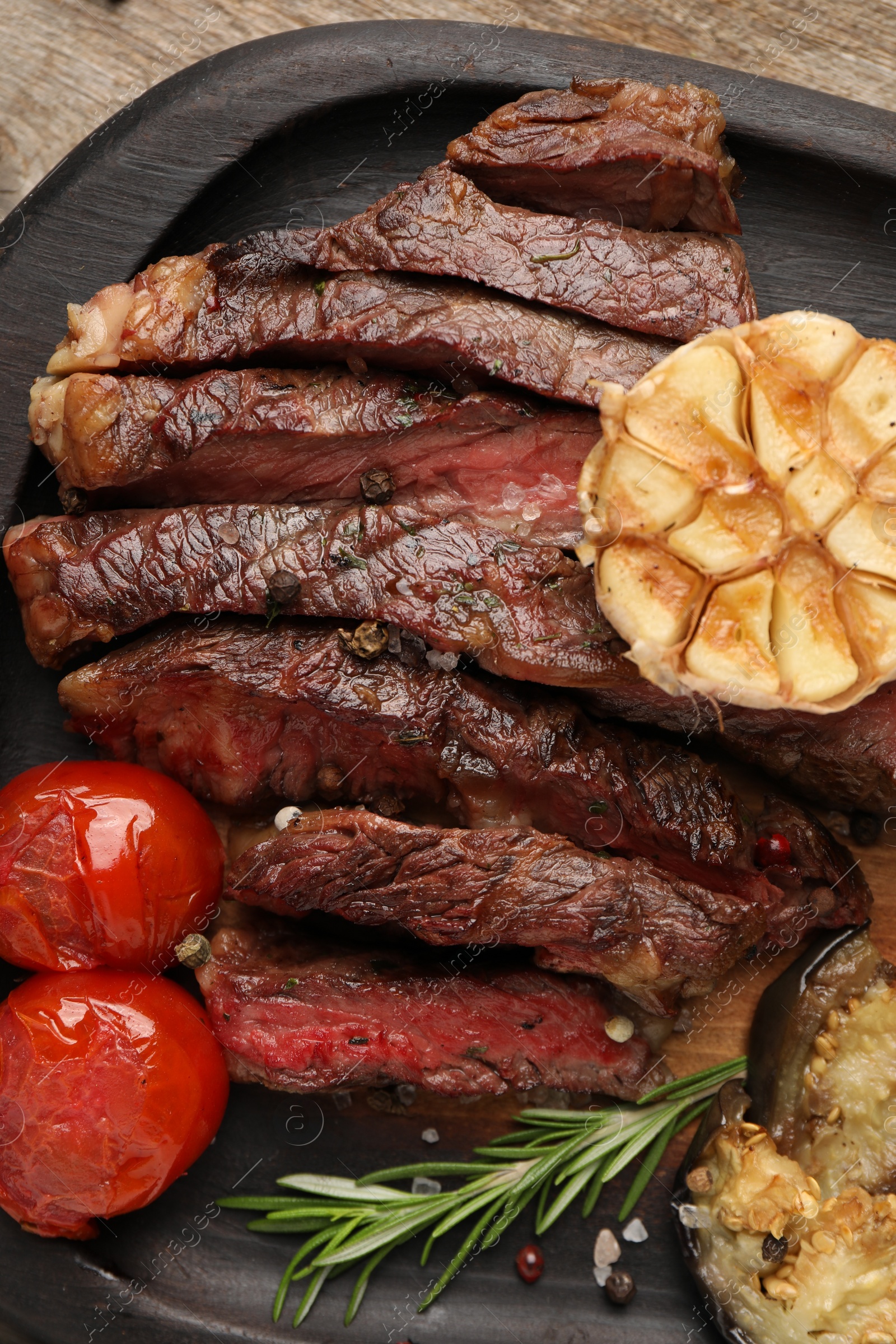 Photo of Delicious grilled beef steak with vegetables and spices on table, top view