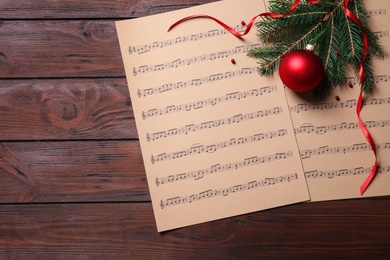 Christmas decorations and music sheets on wooden table, flat lay. Space for text