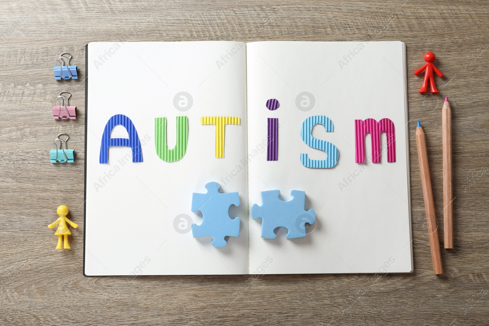 Photo of MYKOLAIV, UKRAINE - DECEMBER 30, 2021: Notebook with word Autism, toys and stationery on wooden table, flat lay