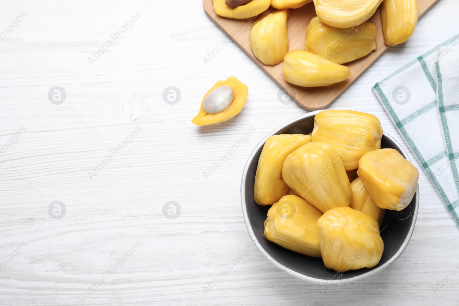 Photo of Delicious exotic jackfruit bulbs on white wooden table, flat lay. Space for text