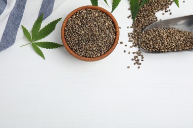 Flat lay composition with hemp seeds on white wooden table, space for text