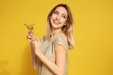 Beautiful young woman with glass of martini cocktail on color background